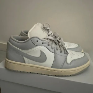 WMNS Air Jordan 1 Low - Jordan 1 Low Coconut Milk Neutral Grey. Skorna har klassisk snörning och rund tå. Använda bara 2 gånger men skorna är som i nytt skick. Normala i storlek. Sköna o riktigt snygga. 