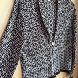 Mönstrad marin/ljusblå kavaj-kofta i bomull  - Snygg stickad kavaj-kofta i marint och ljusblått med grafiskt mönster. Koftan har lång ärm, v-ringad öppning som stängs med en knapp av pärlemor framtill. Väldigt mjuk, helt i bomull, jättesnygg till jeans, marinblått.