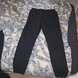 Svarta mjukisbyxor med resår - Svarta mjukisbyxor med resår i midjan och vid bensluten. Byxorna har en enkel och clean look, perfekta för chill dagar eller vid träning. Materialet känns mjukt och skönt mot huden.