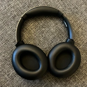 Philips Over-Ear Trådlösa Hörlurar - Snygga svarta Philips over-ear hörlurar med trådlös anslutning. Mjuka öronkuddar och justerbar bygel för hög komfort. Hörlurarna är i mycket gott skick med minimalt slitage, perfekt för musik, film och samtal. Modern design och bra ljudkvalitet.