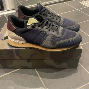 Valentino Garavani Rockrunner strlk 42 - Snygga Valentino Garavani Rockrunner sneakers i 42 säljes! Skicket är bra och använt ett fåtal gånger. Men säljer de då jag inte har ingen användning för de. Pris kan absolut diskuteras vid en snabb affär. Box och dustbag finns, ej något kvitto men de är äktigshets checkade. Storleken passar de med 43 då det är italienska storlekar. 