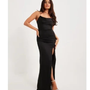 Långklänning  - En svart långklänning i satin med slits på sidan och korsad rygg. Storlek 36. Från Nelly. Endast använd en gång så i väldigt bra skick. Säljer för 285 🫶🏽🖤