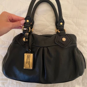 Marc Jacobs väska - Svart väska med guldiga detaljer från Marc Jacobs, äktahetsbevis, dustbag och original box finns som såklart går att få bilder på!