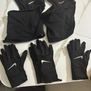 Svarta Nike löparhandskar - Svarta, tunna och smidiga löparhandskar från Nike med vit logga på ovansidan. Perfekta för träning utomhus när det är kallt. Snygg minimalistisk design med lång mudd och mjukt, stretchigt material som sitter tajt på handen. 1 par handskar 180kr alla 3 för 300kr äkta allte med 2 mask 600kr 1 st mask kostar 250 2 st för 400kr allt kostar 600kr med 3 par handskar och 2 mask