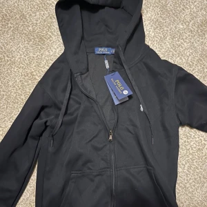 Svart Polo Ralph Lauren zip hoodie - En helt ny polo Ralph Lauren zip hoodie i svart storlek S. Aldrig använd och jättte skön tröja.