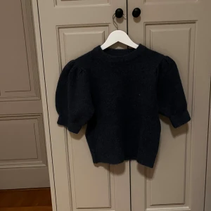 Mörkgrå stickad tröja Gina Tricot - Mysig mörkgrå stickad tröja från Gina Tricot med puffiga trekvartsärmar och rund hals. Tröjan har en loose passform och är perfekt för dig som gillar enkel men trendig stil. Passar dig som vill ha något bekvämt och snyggt till hösten och vintern.