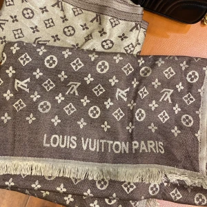 Malin  halsduk  -  mörkbrun med beige detaljer och beige med bruna detaljer. Halsduken har fransad kant och är mjuk och lyxig, perfekt för att lyfta din outfit.