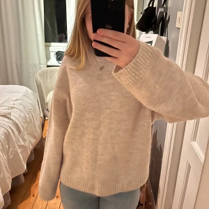 Beige stickad tröja från Gina Tricot - Mysig beige stickad tröja från Gina Tricot med rund halsringning och ribbade muddar. Tröjan har en loose passform och är perfekt för lager-på-lager under kyliga dagar. Aldrig använd 💓