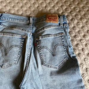 Levi's 501 ljusblå jeans W29 L29 - Klassiska Levi's 501 jeans i ljusblå tvätt med raka ben och femficksdesign. Jeansen har den ikoniska läderpatchen bak i midjan och röda Levi's-tag på bakfickan. Tillverkade i slitstarkt bomullsjeansmaterial, perfekt för en avslappnad och tidlös look.