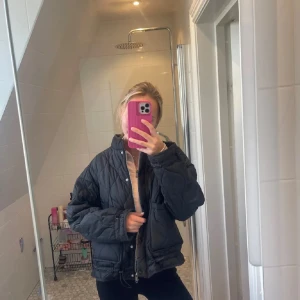 Svart quiltad jacka från Object - Quiltad svart jacka från Object med hög krage och dragkedja framtill. Jackan har två stora fickor och snygga sömmar som ger en cool look.🥰