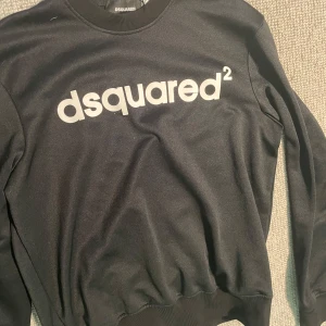 Svart sweatshirt från Dsquared2 - Svart sweatshirt från Dsquared2 med stor vit logga framtill. Tröjan har rund halsringning, långa ärmar och ribbade muddar vid ärmslut och nederkant. Perfekt för en stilren och trendig look. Pris kan diskuteras 