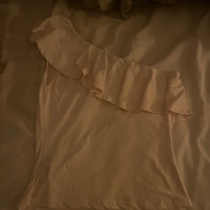 One shoulder topp - Krämvit/ gulaktig one shoulder topp med volangliknanade detalj , storlek S