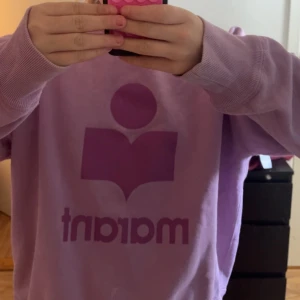  Intressekoll på minLjuslila Marant sweatshirt - Superfin ljuslila sweatshirt från Marant med ikoniskt tryck i mörklila framtill. Tröjan har rund halsringning, långa ärmar och ribbade muddar. Perfekt för dig som gillar en chill och trendig stil.