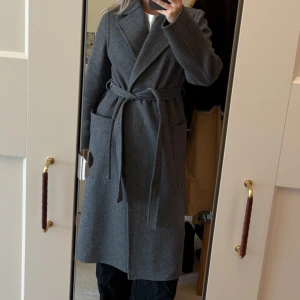 Kappa i ull/kashmir från H&M - Snygg grå kappa från H&M i ull- och kashmirblandning. Lång modell med bred krage, stora fickor och knytskärp i midjan. Stilren och klassisk! Oanvänd🥰 lägger ut för intressekoll!