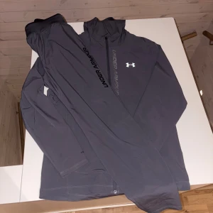  Under Armour Set💥 - ✨ Setet innehåller: Träningsjacka med dragkedja, huva och klassisk Under Armour-logga på bröstet. Perfekt som överdrag innan, under eller efter träningspasset. Matchande byxor med bekväm resår i midjan och diskret Under Armour-tryck längs benet. Ger både stil och rörelsefrihet. 🖤 Färg: Mörkgrå – en tidlös nyans som passar till allt och alltid ser fräsch ut.     (OBS DRAGKEDJAN ÄR TRASIG MEN DET GÅR FOTFARANDE ATT KNÄPPA UPP JACKAN FELFRIT, GÅR SÄKERT ATT FIXA DRAGKEDJAN HOS NÅGON KUNNIG‼️)