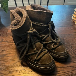 Svarta boots från Inuikii i mocka - Säljer ett par svarta boots från Inuikii med grova snören och mjukt foder. Skorna är tillverkade i mocka och skinn, perfekta för kalla dagar. De har en rund tå och platt sula, samt synlig logga baktill. Grymt snygga och varma för vintern!