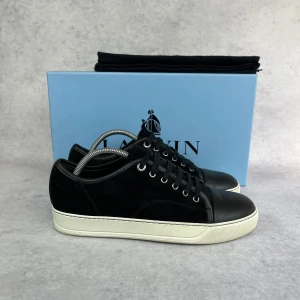 LANVIN DBB1 CAP TOE SNEAKER -  – Condition: 9/10  - Size: 40/UK6  – What is included: Dustbag  – Retail price: 6000 + SEK  Please note that Lanvins fit big and our recommendation is to go one size down