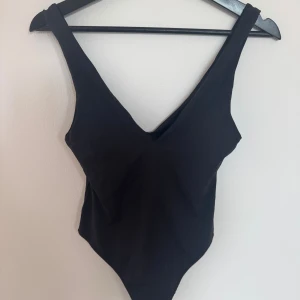 Svart body från Zara med v-ringning - En stilren svart body från Zara med djup v-ringning och breda axelband. Oanvänd