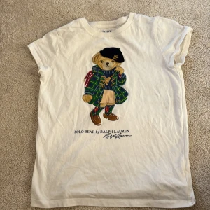 Vit Polo Bear t-shirt från Ralph Lauren - Vit t-shirt från Polo Ralph Lauren med  Polo Bear-tryck framtill. Klassisk rund hals och korta ärmar. Skön och mjuk i bomull, pris kan diskuteras men den är mycket dyr nypris