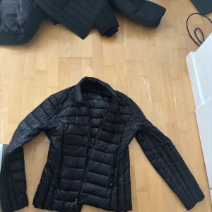 Svart pufferjacka från Armani Exchange - Säljer en svart pufferjacka från Armani Exchange i storlek M. Jackan har quiltad design, dragkedja framtill och en stilren look. Perfekt för dig som vill ha en lätt och snygg jacka med modern känsla.