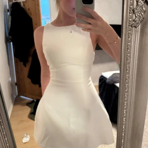 Showpo klänning  - Supersnygg vit mini klänning från Showpo  med båtringning och figurnära midja som går ut i en lätt utsvängd kjol. Klänningen är ärmlös och har en stilren, enkel design med dragkedja i ryggen. Perfekt för dig som gillar minimalistisk och chic stil.