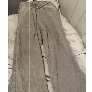 Gråa vida linnebyxor med snörning - Säljer ett par gråa linnebyxor med vida ben och snörning i midjan. Byxorna har en avslappnad passform och är tillverkade i ett luftigt linnematerial med lätt struktur. Perfekta för varmare dagar och chill outfits.