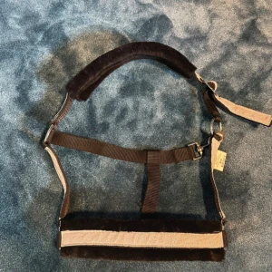 Glittrig grimma med svart fluff -  Grimman har justerbara remmar och är klädd med mjukt material för extra komfort. Perfekt för dig som vill ha en stilren och bekväm grimma till hästen. Använd 1 gång, säljer då den va för liten för min häst 