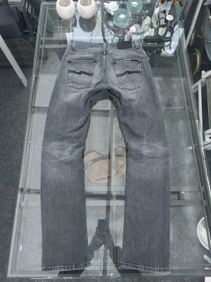 Nudie Jeans Grim Tim Slim Fit – Pale Grey – W30 L34 - Säljer ett par Nudie Jeans Grim Tim i färgen Pale Grey. En ikonisk slim fit-modell med rak siluett som sitter snyggt och funkar till både streetwear och mer minimalistiska outfits.  Jeansen är i mycket bra skick, sparsamt använda och utan hål, fläckar eller andra defekter. Tillverkade i 98 % bomull och 2 % elastan, vilket ger en skön stretch och bekväm passform hela dagen. En tidlös grå tvätt som är lätt att matcha året runt.  Perfekt val för dig som vill ha kvalitetsdenim från ett välkänt märke