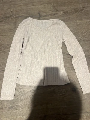 Beige ribbad långärmad topp Shein - Beige ribbad långärmad topp från Shein med v-ringning. Tunn och stretchig, perfekt att styla med jeans eller kjol. Enkel och stilren design som passar till många olika looks.