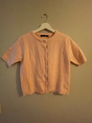 Söt rosa stickad tröja XS - ny med knappar - Stickad tröja från Lager 157 i storlek XS. Helt ny och aldrig använd. Prislappen sitter kvar men priset är borttaget då den var en julklapp. Superfin modell med knappar framtill. Färgen är mer rosa i verkligheten än på bilderna. 