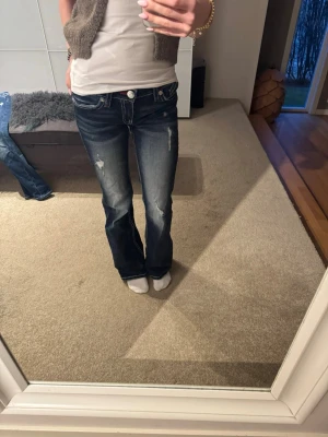 Blå bootcut jeans med slitningar - Snygga blå bootcut jeans med slitna detaljer och kontrastsömmar. Jeansen är knappt använda och har därav inga slitningar💕