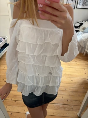 Vit offshoulder blus med volanger - Säljer en superfin vit offshoulder blus med flera lager volanger. Finns ingen lapp men skulle säga xs-s💕