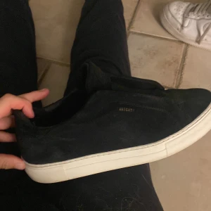  Axel Arigato 360 laceless - Säljer ett par svarta sneakers från Axel Arigato i mocka med vit, platt sula. Skorna har minimalistisk design utan snörning och diskret logga i guld på sidan. Perfekta för dig som gillar stilrena och cleana skor med premiumkänsla. Knappt använda en tvätt som nya, kollar intresse kom med bud