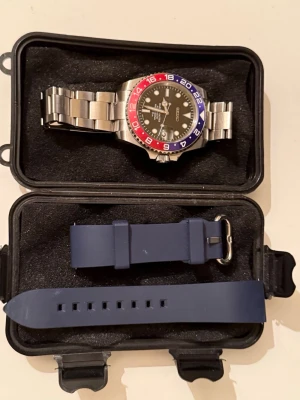 Seiko pepsi mod - Stilren klocka och Design med svart urtavla och Pepsi bezel i rött och blått. Armbandet är i rostfritt stål och det medföljer även ett extra blått silikonband. Klockan har tydliga siffror och sportig look, perfekt för dig som gillar detaljer. Det är en seiko pepsi mod 40mm