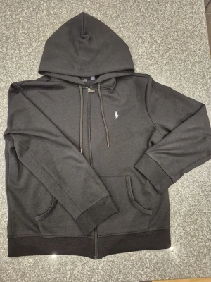 Svart hoodie från Polo Ralph Lauren - Stilren svart zip-tröja från Ralph Lauren. Klassisk design som funkar perfekt både till vardags och mer uppklätt. Mjuk och skön i materialet, lätt att matcha med det mesta. Ett tidlöst plagg från ett välkänt märke. Storlek M men skulle även passa S. Priset är inte hugget i sten, ge rimliga bud!