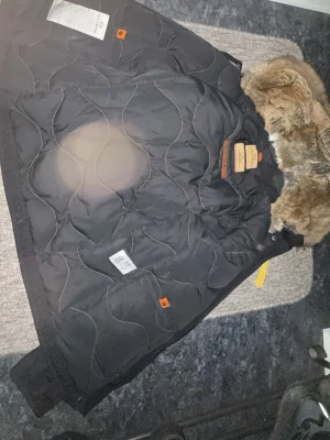 Svart dunjacka med päls från Parajumpers - Säljer en svart dunjacka från Parajumpers med quiltad insida och stor päls runt huvan. Jackan har snygga detaljer och klassisk Parajumpers-logga. Perfekt för kalla dagar och riktigt varm. Passar dig som vill ha både stil och funktion.