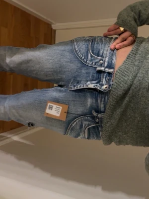 Replay ljusblå jeans med slitningar - Säljer ett par ljusblå jeans från Replay med snygga slitningar och tvättade detaljer. Modellen har låg midja och raka ben, klassisk femficksdesign och tydliga sömmar. Perfekta för en avslappnad och trendig look.