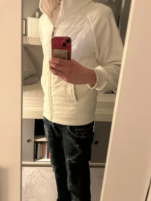 Cardigan jacka - Säljer en vit cardigan jacka. Jackan har huva, två fickor med dragkedja. Jackan är använd bara en gång. Den kommer ifrån ett djur och rök fritt hem .