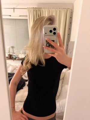 Svart tight t-shirt - Enkel och stilren svart t-shirt med tight passform och korta ärmar. Perfekt basplagg som funkar till allt och är lätt att matcha med andra kläder. Mjuk och skön mot huden.