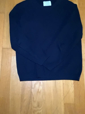 Mörkblå stickad tröja från ZARA - En stilren mörkblå stickad tröja från ZARA i storlek 152. Tröjan har långa ärmar och en klassisk rund halsringning. Perfekt för lager-på-lager och enkel att matcha med olika outfits. 