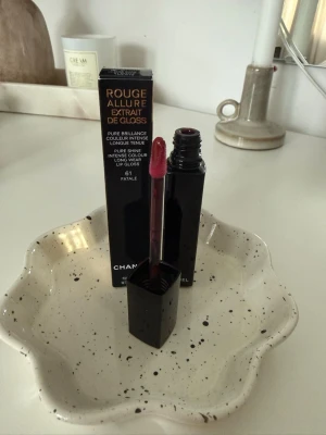 Chanel Rouge Allure Gloss - Chanel Rouge Allure Gloss – 61 Fatale (NY)  Helt nytt och oanvänt läppglans från Chanel Serie: Rouge Allure Gloss Nyans: 61 Fatale Glansig finish med fyllig och återfuktande känsla Mängd: 5,5 g  Endast öppnad för fotografering, aldrig testad. Originalförpackning medföljer.                          Nypris ca 450 kr