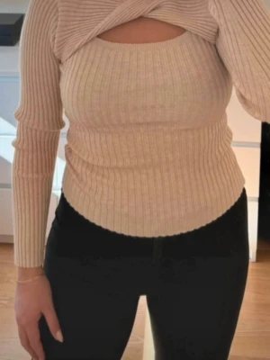 Beige ribbad stickad topp med cut out - Använd en gång (säljs pga den blivit stor på mig) Tvättad. Storlek 38 (passar även en storlek 36).