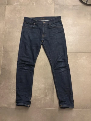Mörkblå Lean Dean jeans från Nudie  - Säljer ett par Lean Dean nudie jeans i tvätten Dry 16 dips, storlek W33, L32, in princip nya, använts några gånger 