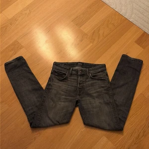jack and jones - Säljer ett par jack and jones jeans i svart tvätt. Klassisk femficksmodell med lite tajtare passform. Jeansen är tillverkade i bomull med en snygg sliten look och subtila detaljer. 