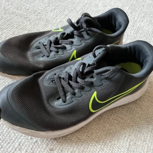 Svarta Nike sneakers med limegrön detalj - Snygga svarta Nike sneakers med limegrön swoosh och detaljer. Ovandel i mesh och syntet med snörning.