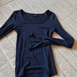 Mörkblå långärmad topp från Gina tricot - En enkel och stilren mörkblå långärmad topp från Gina tricot. Toppen har rundad, djup ringning och är tillverkad i mjuk bomullsmix. Perfekt att styla med jeans eller kjol för en clean look.