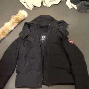 Svart dunjacka från Canada Goose - !Kvitto finns tillgänglig det är bara att DM mig! Säljer en svart Canada Goose dunjacka i modell Fusion S/P. Jackan har huva, dragkedja och knappar framtill samt klassisk logga på ärmen. Perfekt för kalla vinterdagar och riktigt snygg streetstil.