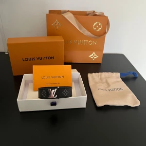Louis Vuitton svart armband  - Säljer ett svart Louis Vuitton armband med klassiskt monogrammönster och silverfärgat LV-spänne. Armbandet har en stilren design med gråa LV-loggor. Kommer med originalbox, dustbag och påse.