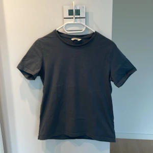 Mörkgrå t-shirt från Holzweiler - Snygg mörkgrå/blå t-shirt i bra skick från Holzweiler med diskret logga på bröstet. 100% bomull 