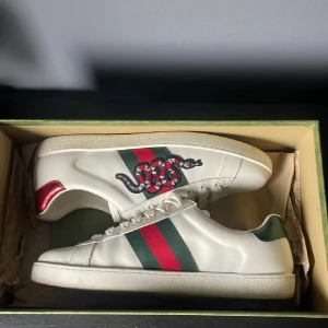 Gucci Ace  - Säljer nu dessa Gucci ace skor i 10/10 skick, du får även med box och en Gucci låda som den fraktas i vid köp, så allt på bilden ingår. Nypris: 7000-8000 mitt pris: 2399. Skriv vid fler frågor eller funderingar! Pris går att diskutera